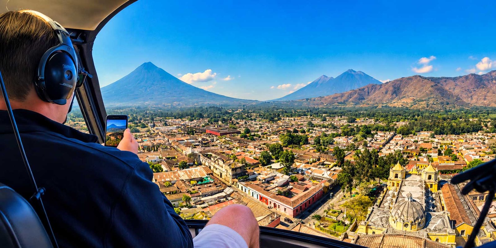 Antigua Guatemala helicopter tour with aerial views of the colonial city, historic churches, and surrounding volcanoes from inside the helicopter.