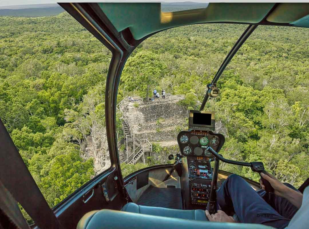 el-mirador-helicopter-tour-aerial-view El Mirador Helicopter Tour approaching an ancient Maya pyramid above the Petén rainforest in Guatemala, viewed from inside the helicopter cockpit.